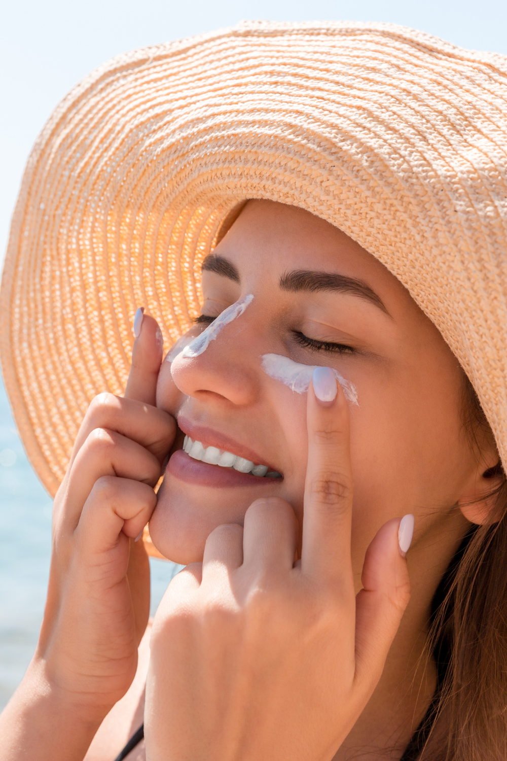 Flat lay of summer UV essentials: SPF lotion, wide-brim hat, sunglasses, and water bottle — representing sun safety preparedness.