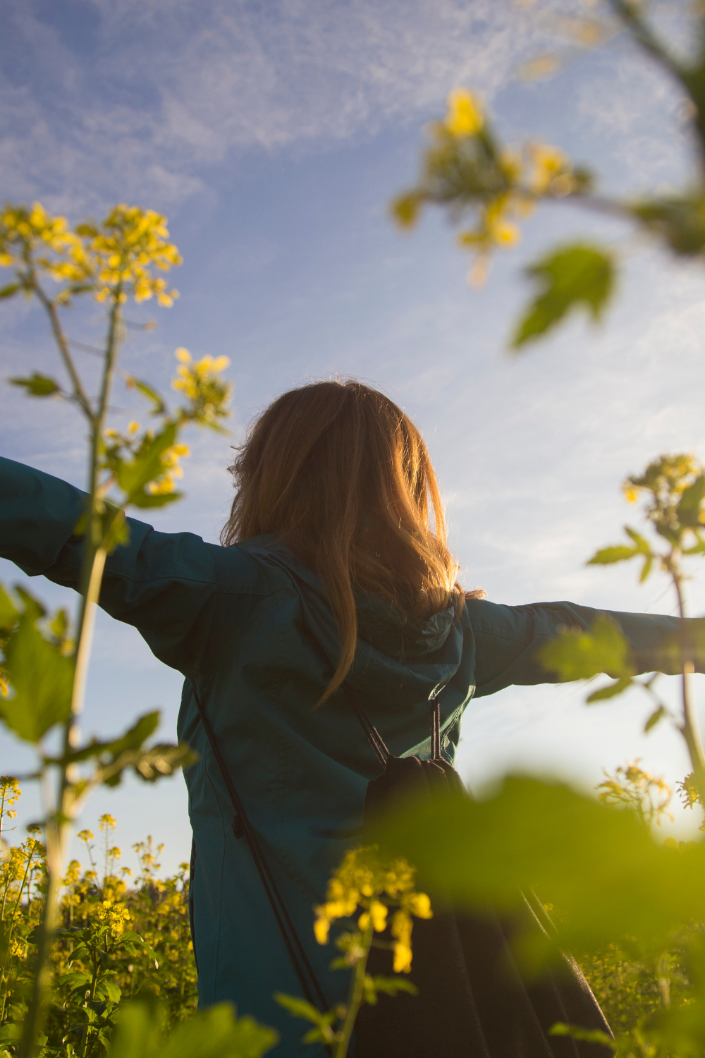 A joyful woman standing in a forest with her arms wide open, embracing nature and expressing freedom, peace, and mental wellness.